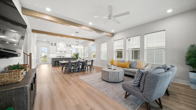 living area with a wealth of natural light, baseboards, beam ceiling, and light wood-style floors