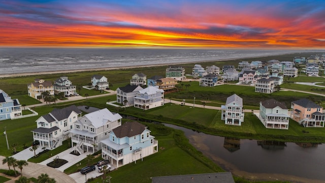 aerial view at dusk featuring a beach view and a water view