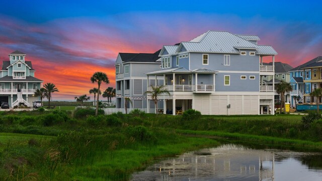 rear view of property featuring metal roof, a water view, a residential view, and a standing seam roof