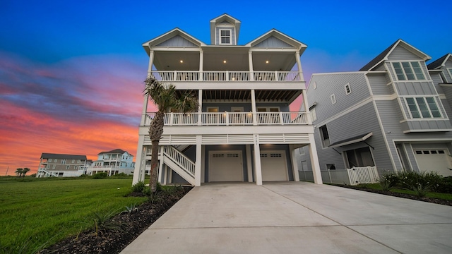 view of front of property featuring driveway, board and batten siding, an attached garage, a front yard, and a balcony