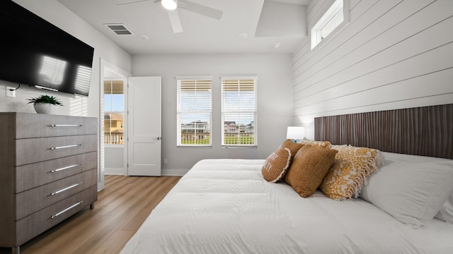 bedroom featuring light wood finished floors, visible vents, multiple windows, and a ceiling fan