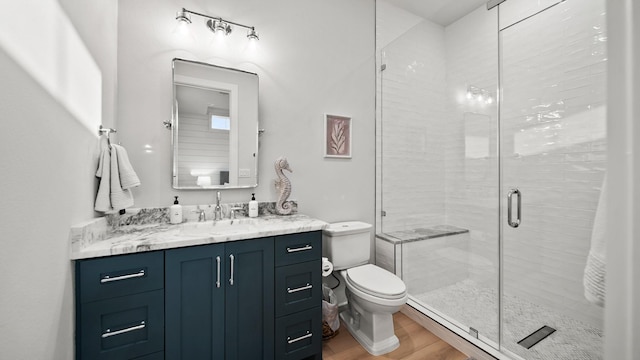 full bath featuring vanity, toilet, wood finished floors, and a shower stall