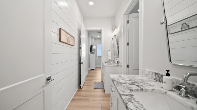 bathroom featuring wooden walls, recessed lighting, vanity, and wood finished floors