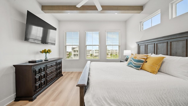 bedroom with light wood finished floors, beamed ceiling, and baseboards