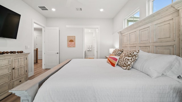 bedroom with recessed lighting, visible vents, light wood-style flooring, and connected bathroom