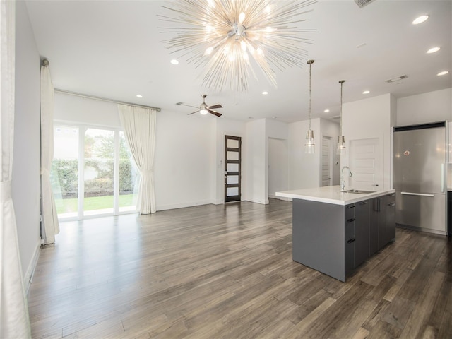 kitchen featuring sink, dark hardwood / wood-style floors, stainless steel fridge, and an island with sink