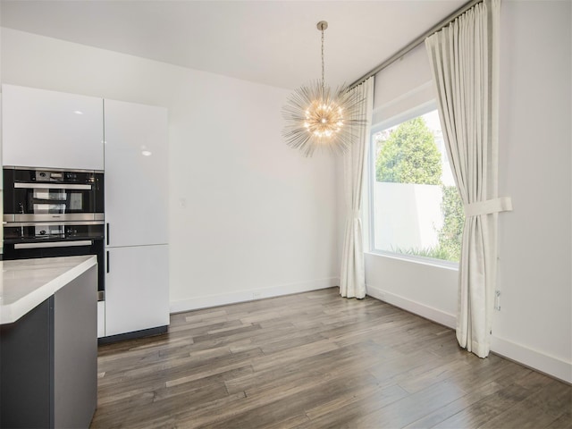 unfurnished dining area with a healthy amount of sunlight, a chandelier, and hardwood / wood-style floors