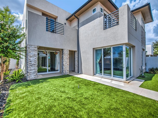 rear view of house with a lawn and a balcony