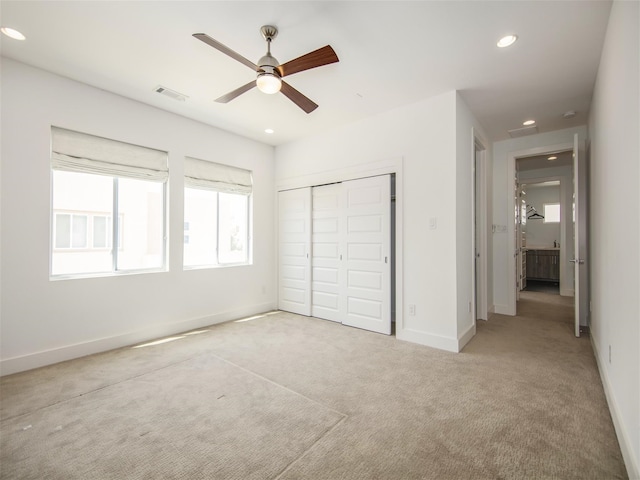 unfurnished bedroom with light carpet, a closet, and ceiling fan