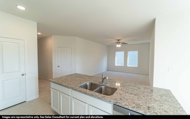 kitchen with white cabinetry, ceiling fan, sink, light stone counters, and light tile patterned floors