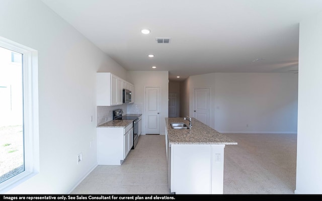 kitchen with sink, a wealth of natural light, electric stove, and a center island with sink