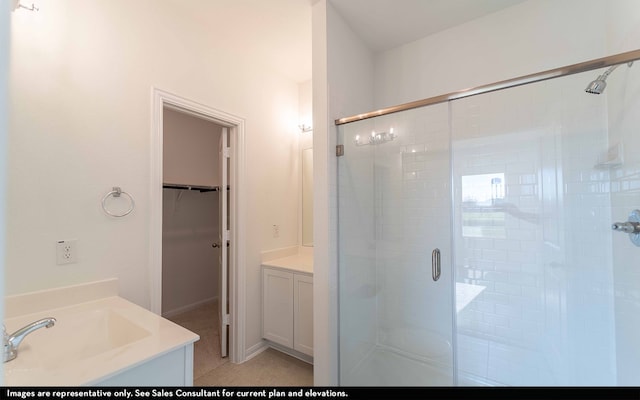 bathroom featuring a shower with shower door, vanity, and tile patterned floors