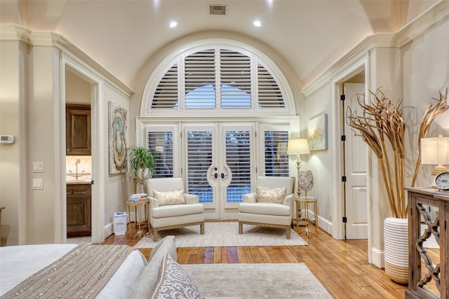 sitting room featuring high vaulted ceiling, light hardwood / wood-style flooring, and french doors