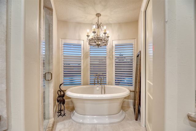 bathroom with a textured ceiling, a bathing tub, and an inviting chandelier