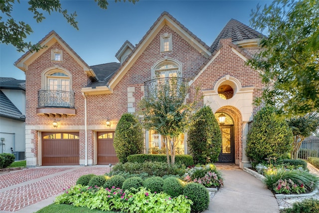 tudor-style house featuring a garage, a balcony, and central AC