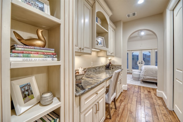 kitchen with french doors, light hardwood / wood-style floors, cream cabinetry, and dark stone counters