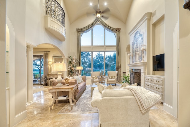 living room featuring ceiling fan, a high end fireplace, a wealth of natural light, and a high ceiling