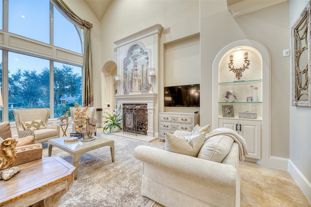 living room with a high ceiling, built in features, and a fireplace