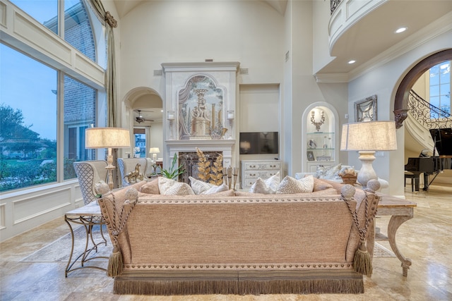 living room featuring ceiling fan, crown molding, and a high ceiling