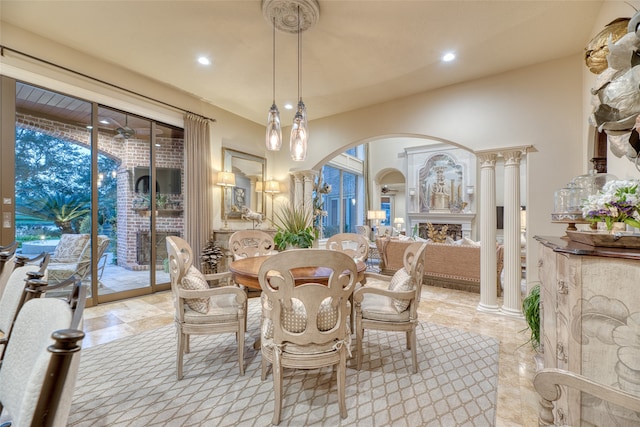 dining space with a fireplace and ornate columns