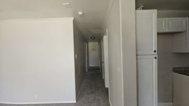 hallway with dark carpet and crown molding