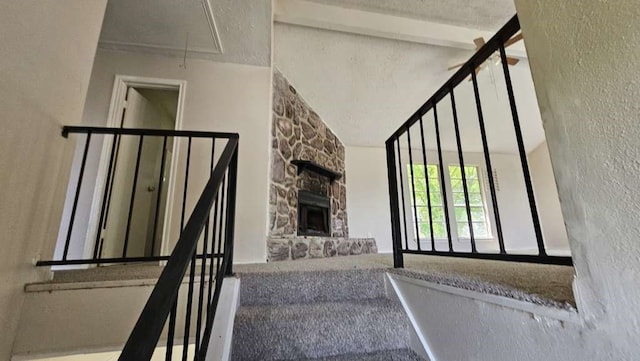 stairway featuring beamed ceiling, carpet, and a fireplace