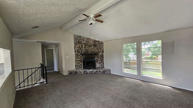 unfurnished living room featuring ceiling fan, dark carpet, a stone fireplace, and lofted ceiling with beams