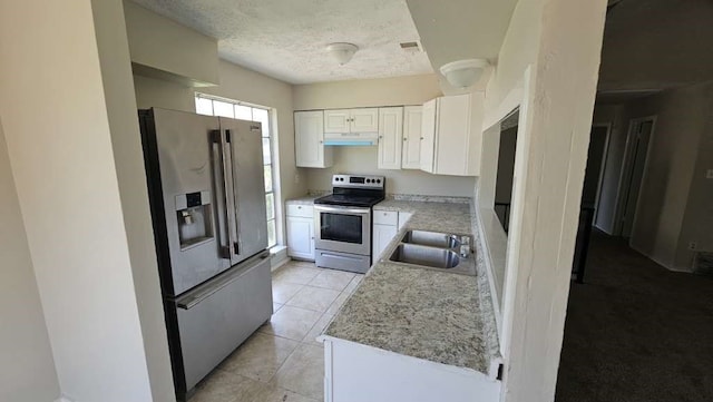 kitchen with appliances with stainless steel finishes, white cabinetry, sink, light stone countertops, and light tile patterned floors