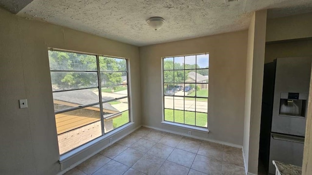 doorway to outside with a textured ceiling and light tile patterned floors