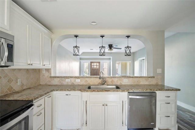 kitchen with white cabinetry, sink, light stone countertops, appliances with stainless steel finishes, and backsplash