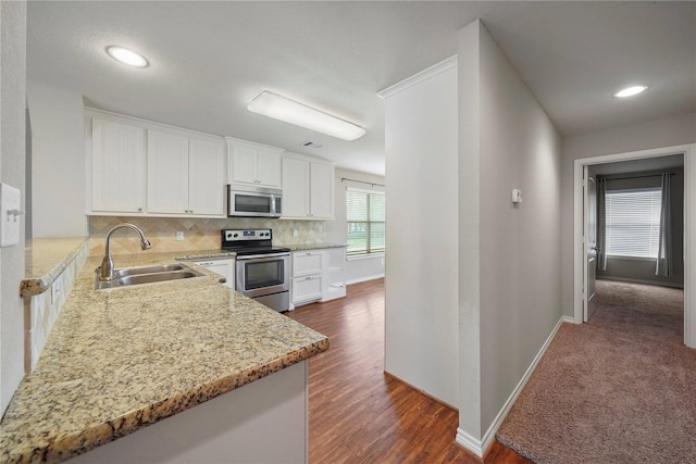 kitchen with stainless steel appliances, sink, dark carpet, light stone counters, and backsplash