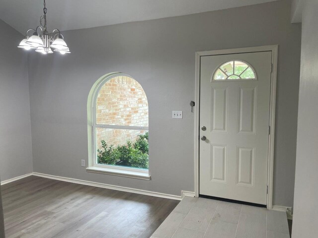 entrance foyer featuring a notable chandelier, wood finished floors, and baseboards