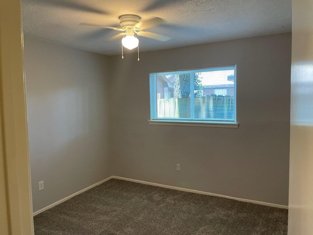 empty room with a textured ceiling, dark colored carpet, ceiling fan, and baseboards