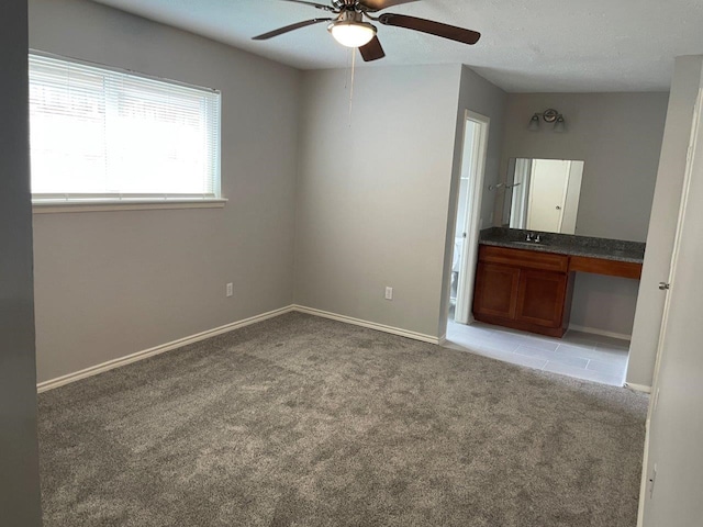 unfurnished bedroom featuring carpet floors, built in study area, a sink, and baseboards