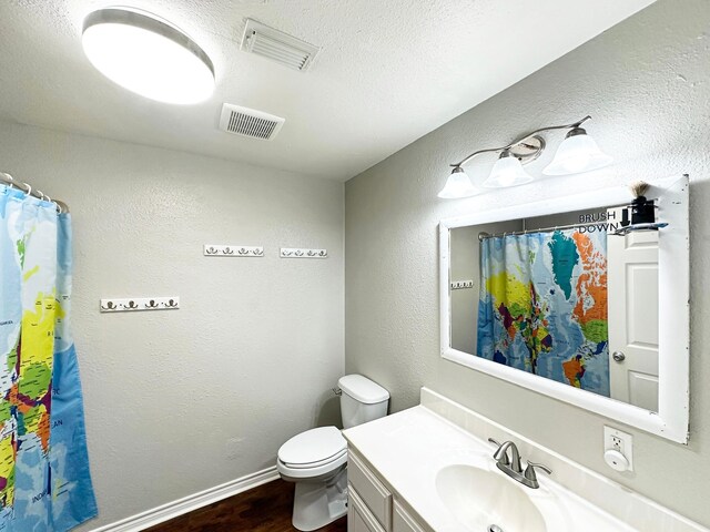 bathroom with hardwood / wood-style floors, vanity, a textured ceiling, and toilet