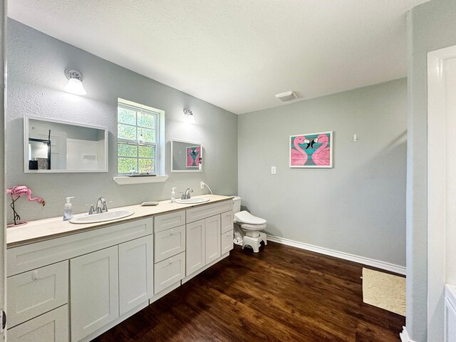 bathroom with toilet, hardwood / wood-style flooring, and dual bowl vanity