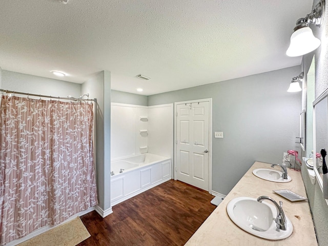 bathroom featuring a textured ceiling, double sink vanity, hardwood / wood-style floors, and shower / bath combo