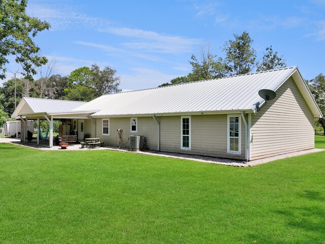 rear view of property featuring central AC unit, a patio area, and a yard