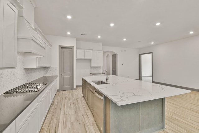 kitchen featuring white cabinets, sink, appliances with stainless steel finishes, a large island, and light stone counters