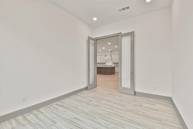 unfurnished room featuring french doors and light hardwood / wood-style floors