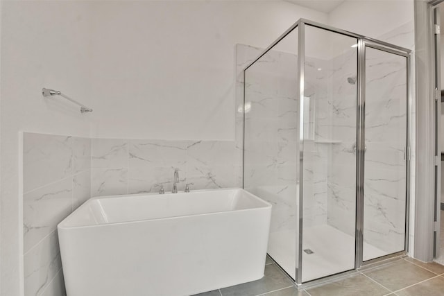 bathroom featuring tile patterned flooring, tile walls, and independent shower and bath