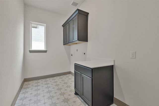 washroom with electric dryer hookup and cabinets