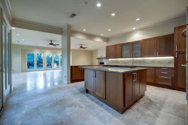 kitchen with a center island, light stone countertops, ceiling fan, and backsplash