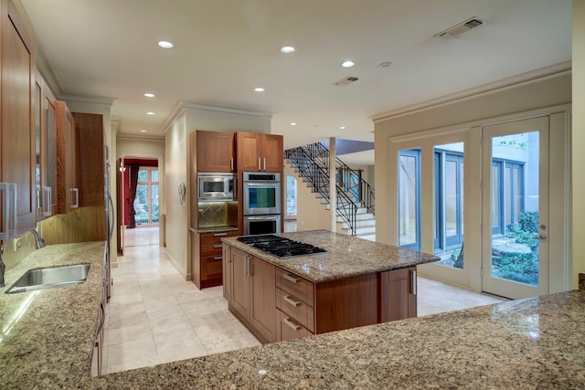 kitchen with sink, light tile patterned flooring, a center island, and light stone countertops