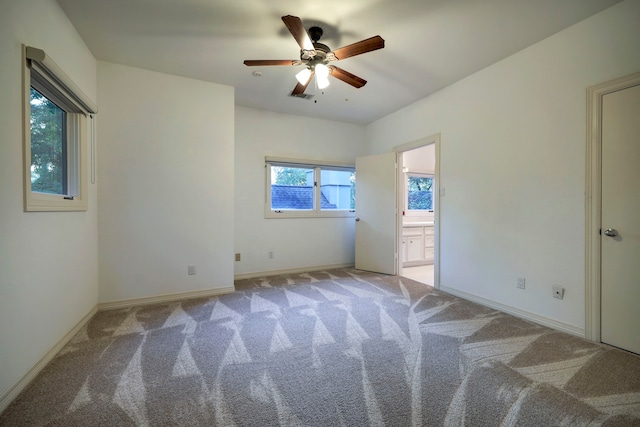 unfurnished bedroom featuring light colored carpet, ensuite bathroom, and ceiling fan