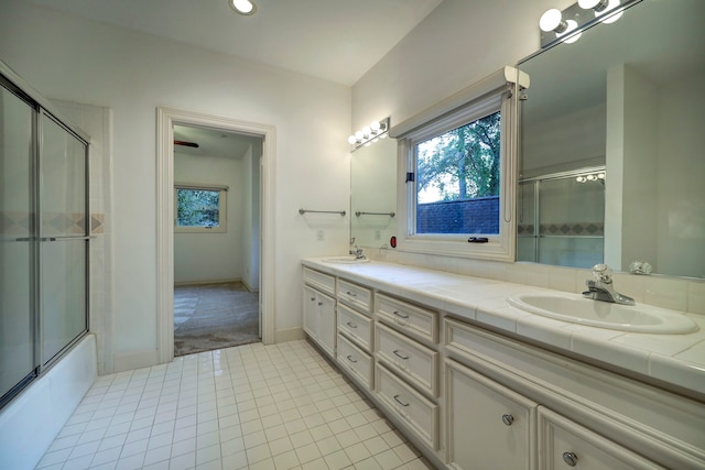 bathroom featuring bath / shower combo with glass door, tile patterned flooring, and dual bowl vanity