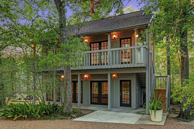 back house at dusk featuring a patio, a balcony, and french doors