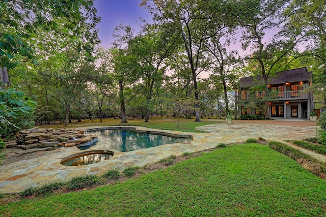 pool at dusk with a yard and a patio area