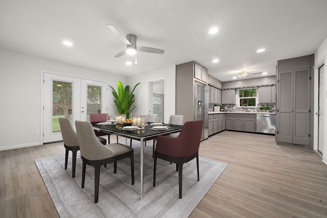 dining room featuring french doors, light wood-type flooring, ceiling fan, and sink