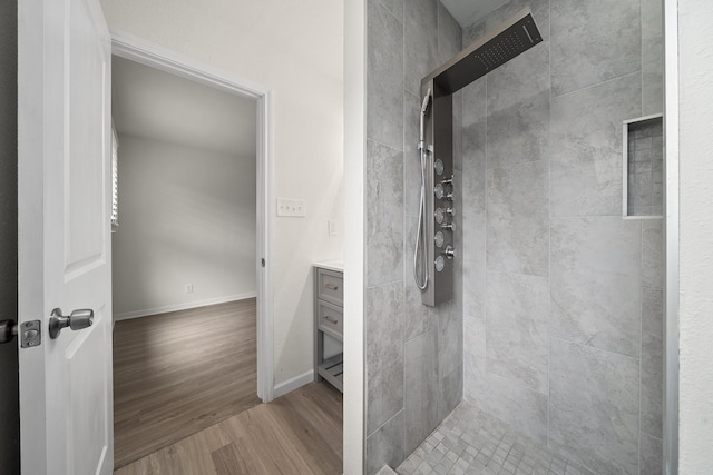 bathroom featuring hardwood / wood-style floors, vanity, and tiled shower